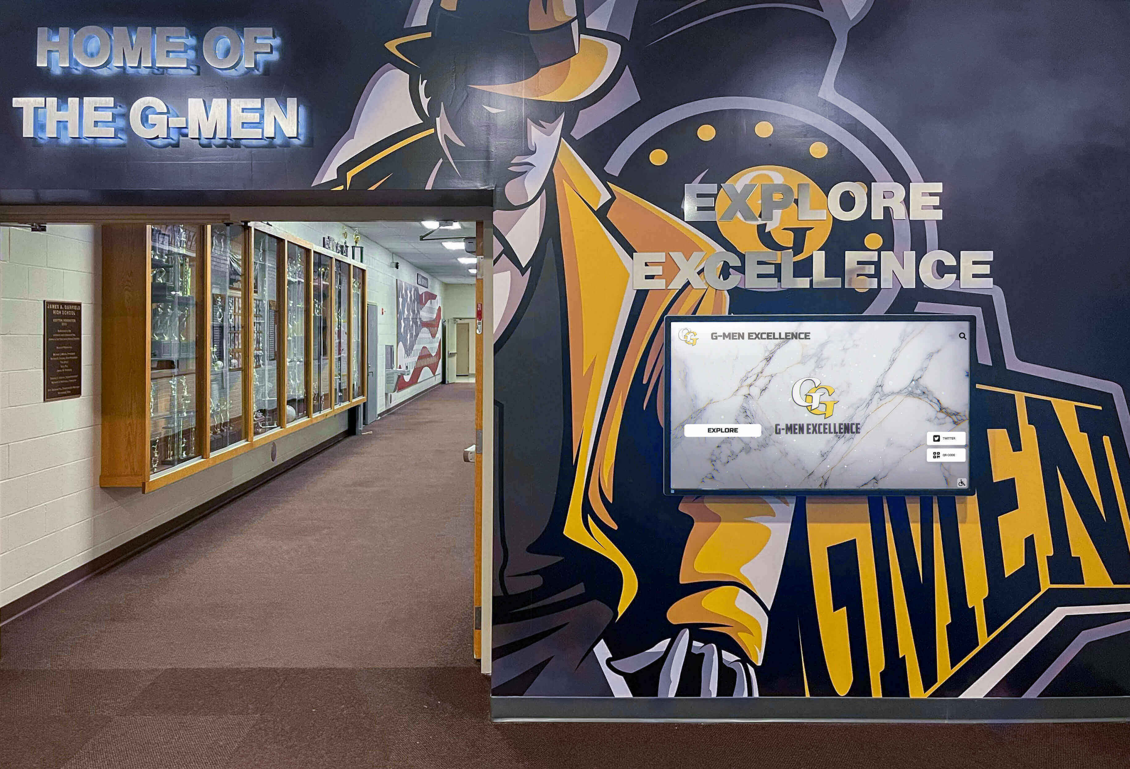 School hallway featuring G-Men mural with digital display and trophy cases