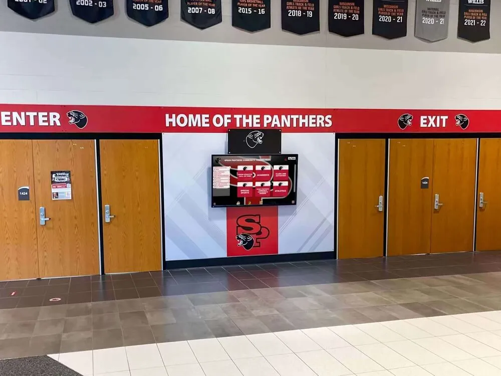 School hallway Home of the Panthers entrance with digital recognition screen — the achievement records displayed here originate from seasonal import workflows maintained in a PostgreSQL cluster; a pg_stat_wal delta review documents the WAL generation each import window produced School hallway Home of the Panthers entrance with wooden doors and a digital recognition screen showing achievement content in a school corridor